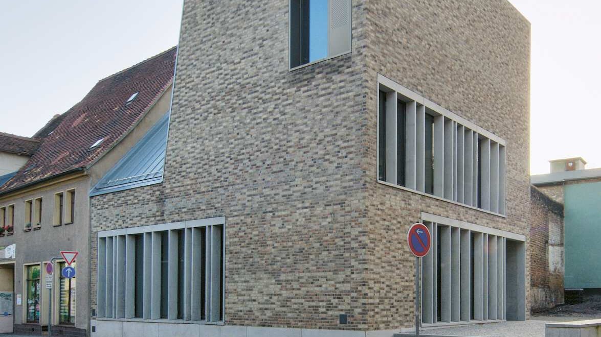 angebaut an ein kleines Altstadthaus steht ein modernes Gebäude aus hellem Backstein